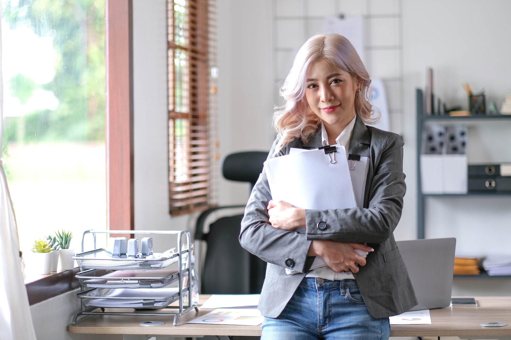 Charming Asian woman with a smile standing holding papers at the office.